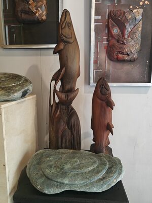 Gallery display of carved stone discs and wooden fish carvings