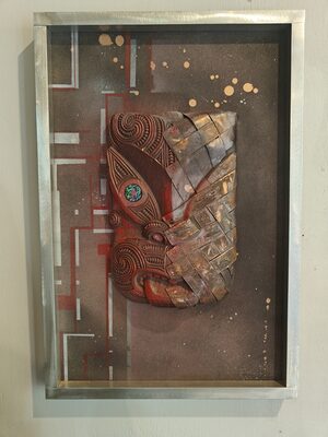 Framed carved panel with a small face on a textured ground
