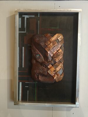Framed artwork of woven copper strips over a carved form