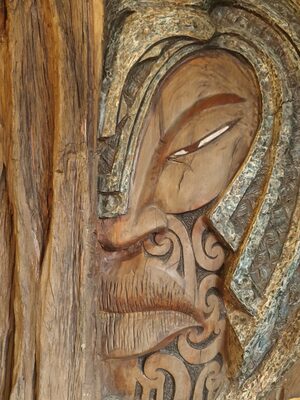 Carved wooden face with stone-inlaid eyes and patterns