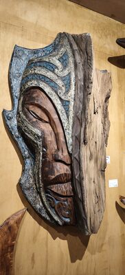Carved wall panel with a face in blue and grey tones