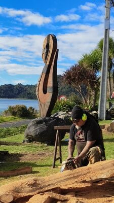 A carver shaping a large log with a chisel