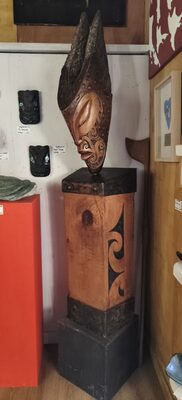 Dark carved figure on a carved pedestal in the gallery