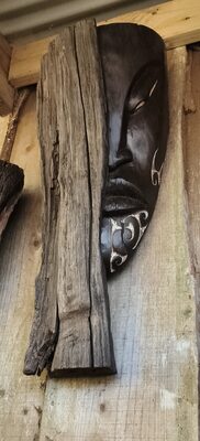 Dark carved face on a weathered post
