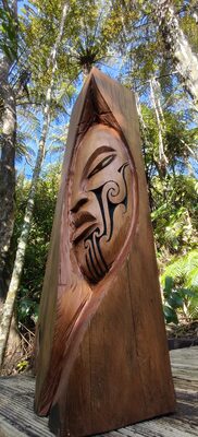 Pointed wooden carving with a face standing in the garden