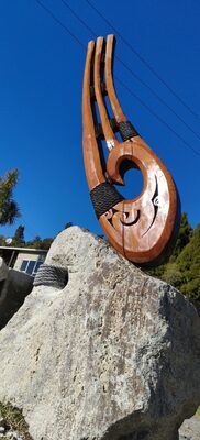 Carved hook sculpture on a rock, blue sky behind