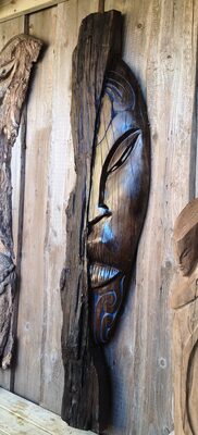 Dark carved face mounted on a timber wall